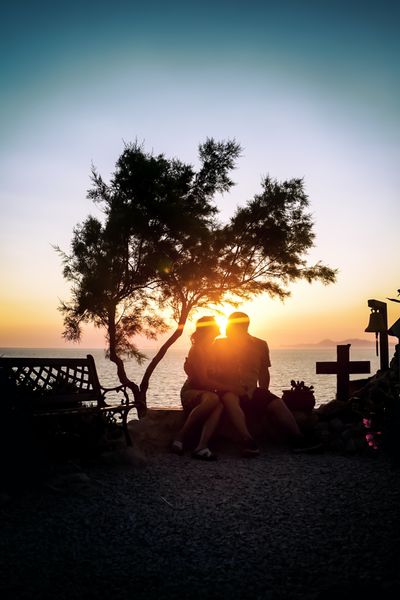 couple sitting by ocean during sunset